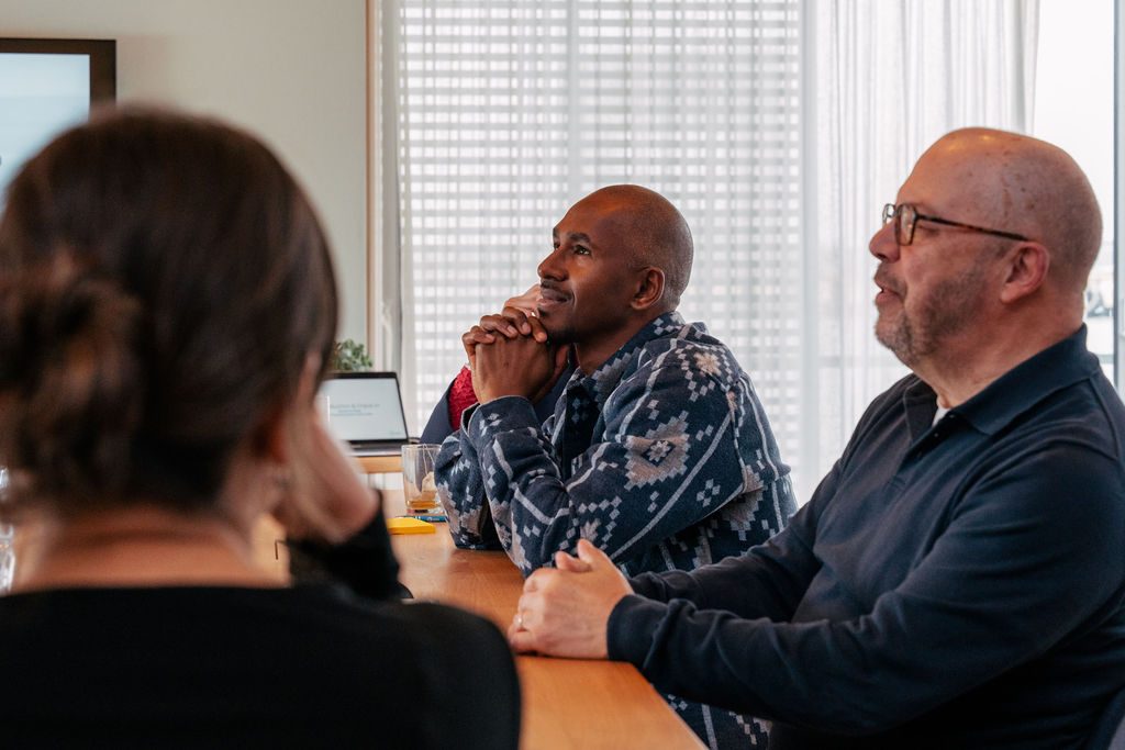 Drie deelnemers luisteren aandachtig tijdens een Human Centric sessie aan tafel