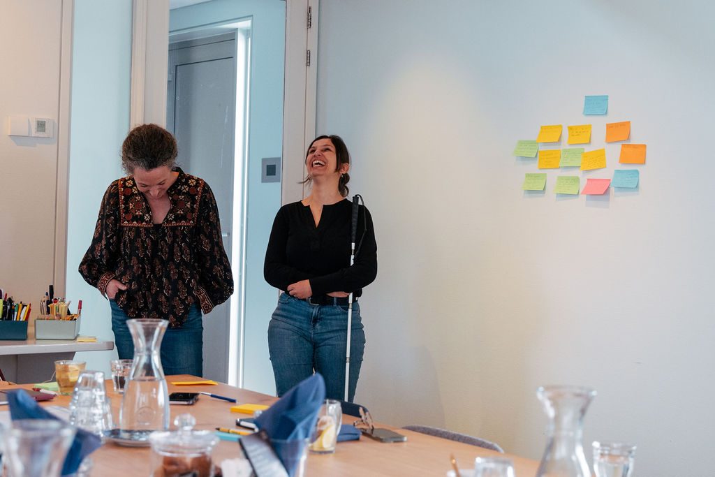 Twee deelnemers in gesprek tijdens een Human Centric workshop, één met taststok