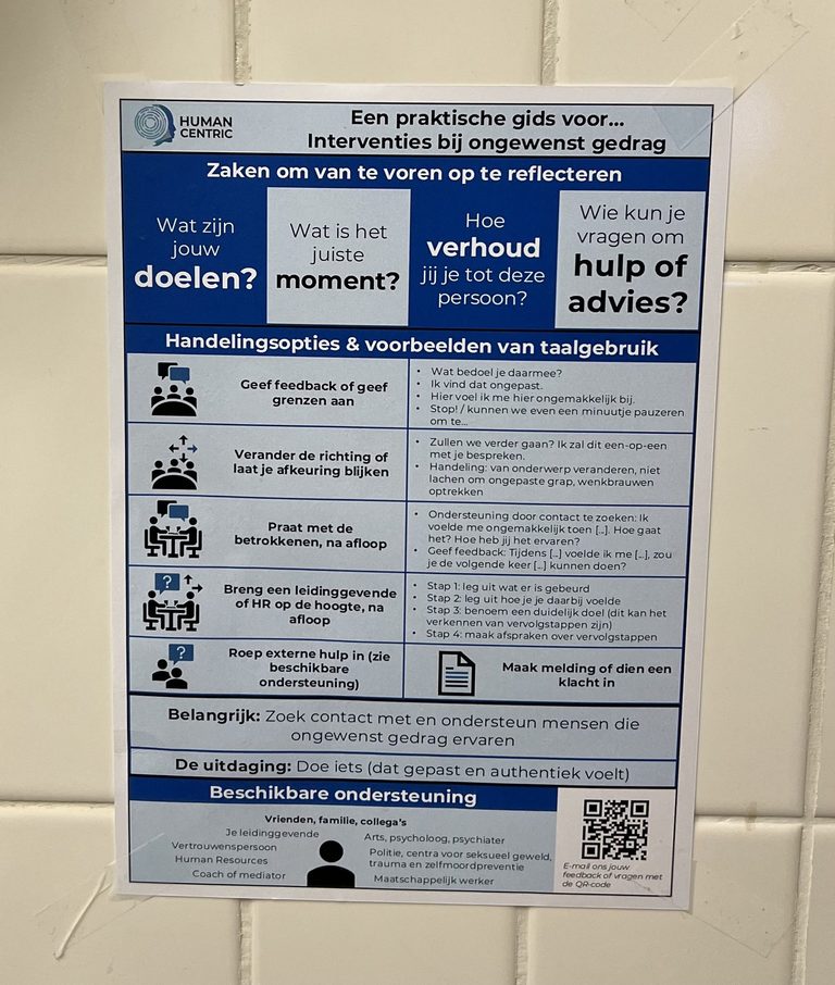 A Human Centric hand-out titled &lsquo;A practical guide to addressing inappropriate behaviour&rsquo; pinned to a tile wall