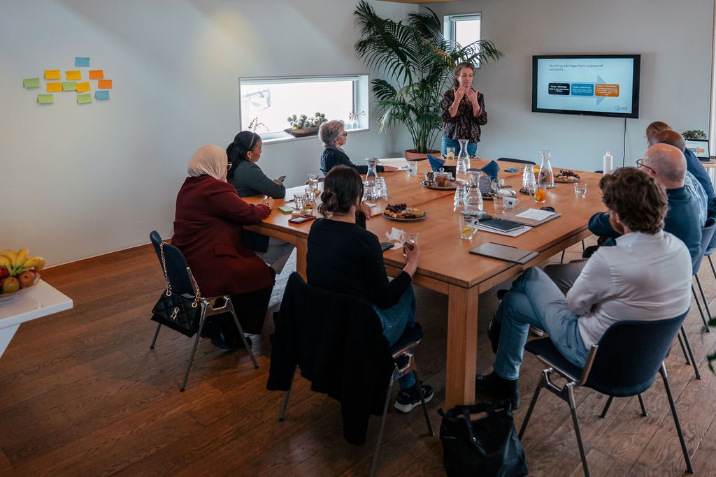 Workshop bij Human Centric: facilitator presenteert aan een diverse groep deelnemers rond een tafel