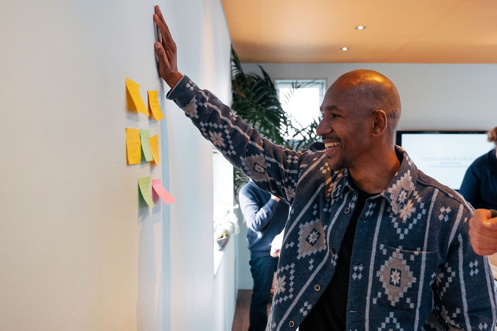 Deelnemer plakt post-its op een muur tijdens een Human Centric workshop