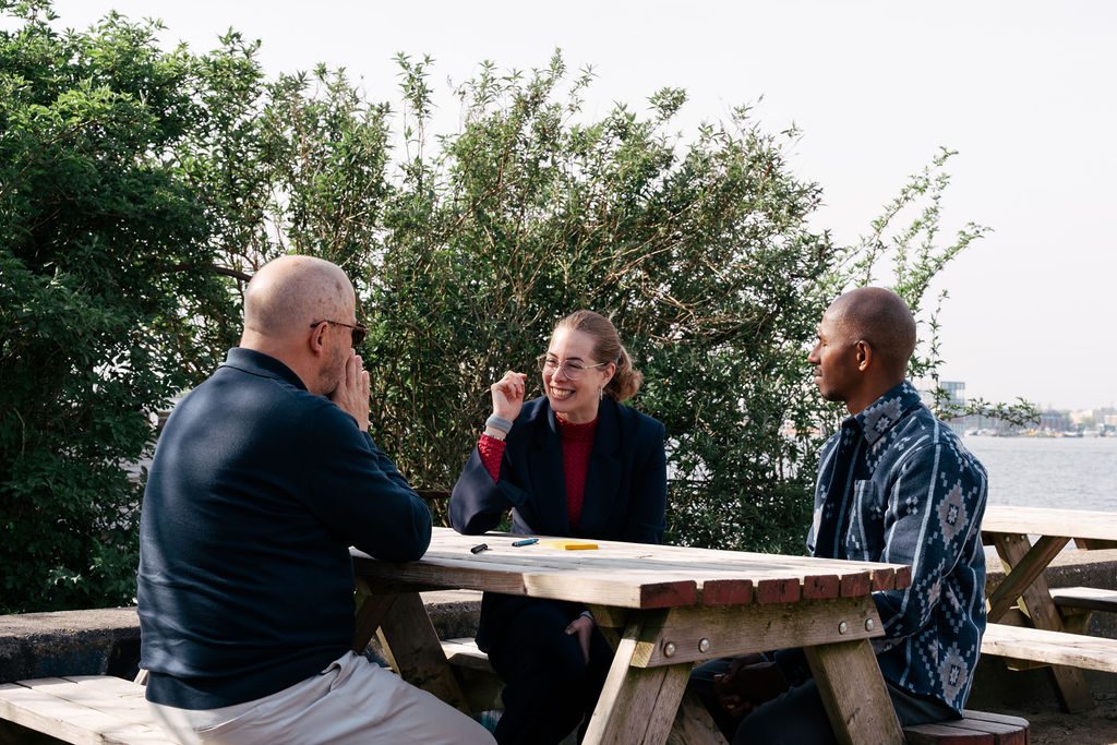 Drie consultants van Human Centric in gesprek aan een buitentafel