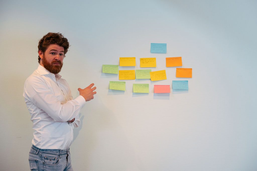 Trainer licht een geclusterde wand met post-its toe tijdens een Human Centric sessie